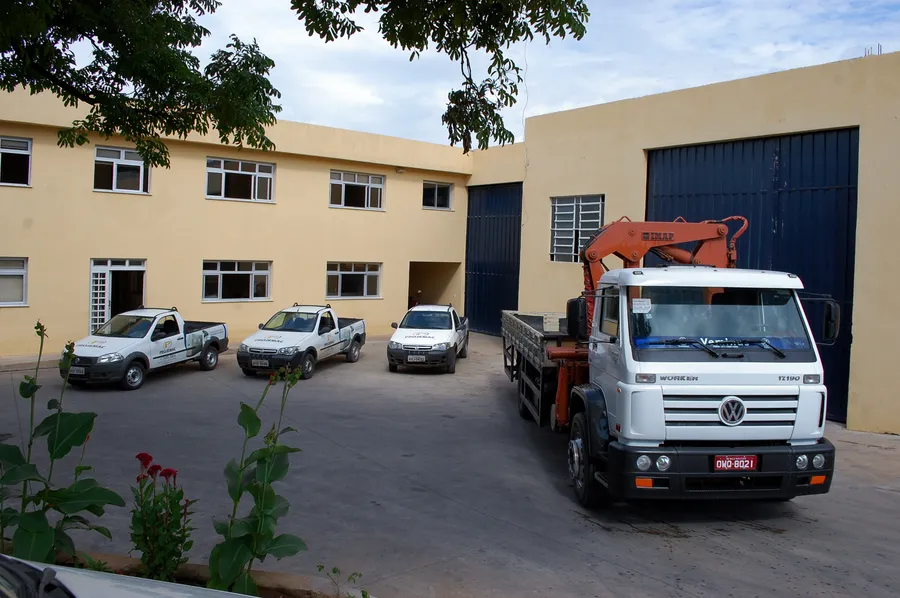 Sede da PROJEMAC com caminhão munck e picapes da frota